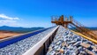 © Matthew - Vibrant view of a railway track with gravel leading to a mining facility under a clear blue sky