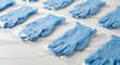 © AntonioHenrique - Multiple blue surgical gloves in clear plastic packaging arranged on a white surface in a pattern