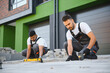 © Serhii - A group of multiracial workers lay paving stones on a sidewalk near a house