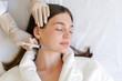 © Home-stock - Cosmetologist performing the chin lift procedure, making beauty injections to young lady, facial rejuvenation treatment, top view