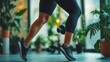 © brayen - Close-up of a person's legs in motion, exercising indoors with weights and plants.