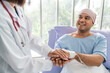 © Chanakon - A male cancer patient in a wheelchair receives IV therapy while a female doctor offers care encouragement and updates on his test results providing support and discussing health progress