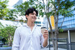 © Kawee - Asian young businessman holding a cup of coffee while walking in city.