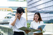 © Kawee - Asian young businessman and woman partner working outdoors in city.