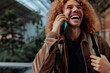 © bernardbodo - Happy tourist laughing while talking on phone in airport