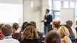© N7 - People listening to speaker presentation in hall — emphasizing attentive learning and discussion