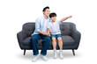 © STOCK88PHOTOGRAPHER - A father and son spending quality time while sitting together on the sofa and pointing in front on PNG background
