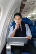 © NINENII - Traveling and technology. young business man working on Laptop and smartphone while sitting in airplane.