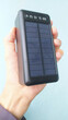 © Nataliia - Hand cradling sleek solar charger, innovation beacon for Earth Day endeavors and Obon Festival's mindful energy renewal rituals