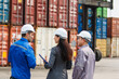 © DG PhotoStock - Team of engineers or workers at a container yard discussing seriously and shaking hands to symbolize teamwork and business success.