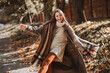 © deagreez - Stylish brunette woman enjoying a sunny autumn day outdoors in a chic coat, surrounded by golden foliage in the park.