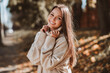 © deagreez - Smiling young woman in casual autumn outfit enjoying a sunny walk in a park filled with vibrant fall foliage