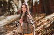 © deagreez - Charming young woman in autumn park enjoying sunshine, wearing stylish coat and scarf, surrounded by beautiful fall foliage