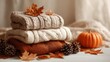 © N_K - Warm autumn sweaters stacked with pumpkin, pine cones and dry leaves – cozy fall fashion, seasonal decor, natural textures, warm colors, lifestyle, cozy home setup, autumn vibes, knitwear essentials