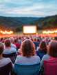 © Kowit - Outdoor movie screening with a large screen set against a scenic backdrop, where a crowd enjoys a film under twilight.