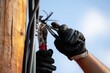 © Creativeraf - Workers gloved hand using pliers to cut a wire on a utility pole