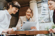 © qunica.com - Three women sharing ideas outdoors, fostering teamwork and collaboration using digital technology.
