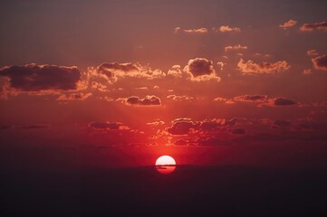 Wall Mural - a blazing red evening sky showcases nature's splendor as the sun sinks beneath the skyline, spreadin