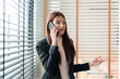 © amnaj - Young businesswoman having a serious conversation on her phone, showing concern and gesturing with her hand