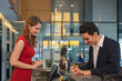 © bigy9950 - The Hotel receptionist and guest are filling out paperwork while checking in at hotel reception desk. staff serving a foreign visitor.
