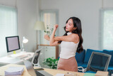 Businesswoman stretching arms while working on computer at office desk, taking a break from work to refresh and relieve stress