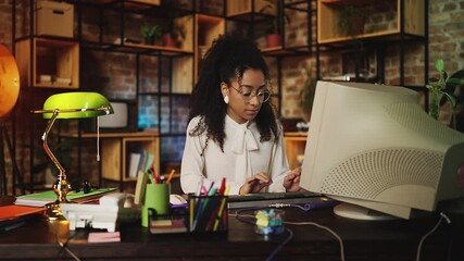 Young African American secretary working on computer in retro style office