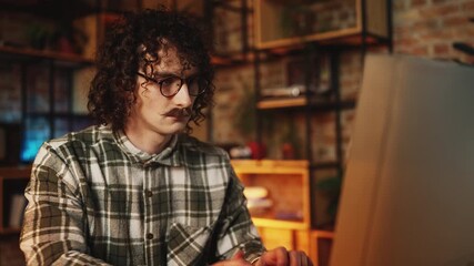Focused male programmer working on computer in retro office, software creation