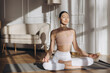 © anatoliycherkas - Young woman practicing yoga lotus pose at home