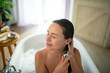 © Halfpoint - Relaxed young woman enjoying self-care and hair wash in bathtub.