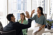 © fizkes - Two Latin male, female colleagues share victorious high-five during briefing meeting, celebrating shared success or breakthrough in business. Teamwork, motivation, and positive friendly work relations