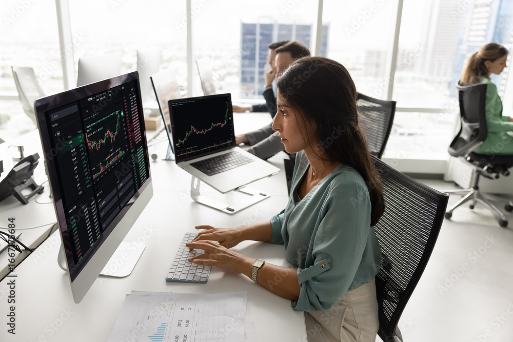 Professional Latina woman sits at desk in coworking office, focused on ...
