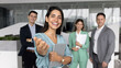 © fizkes - Portrait of businesswoman in foreground smiling confidently, reaching out with welcoming gesture while holding tablet. Leader or project manager inviting collaboration, onboarding client or colleague