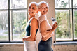© HBS - Two beautiful older women with grey hair wearing sportswear standing in a fitness gym. Motivation, physical activity, and a healthy lifestyle.