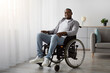 © Prostock-studio - Positive lifestyle, health care, therapy, recovery and treatment in rehab clinic and home. Smiling middle aged african american male in wheelchair, in living room interior with gray wall, free space