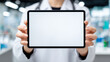 © Rosi - A medical professional holding a blank tablet screen toward the camera, inviting healthcare messaging telemedicine interfaces and patient information presentation and branding.