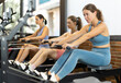 © JackF - Sportive young girls training on cable row machine in large fitness hall during daytime