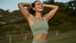 © Lamia - Ai generated image of a fit woman with her hands behind her head, smiling and looking up outdoors in a park with trees