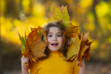 Wall Mural - Kids with Autumn leaves of maple trees backdrop. Child near Autumn fall leaves in sunlight. Little kid in Autumnal fall park. Kids and Foliage, falling leaves. Autumn leaf. Falling leaves.