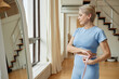 © Seventyfour - Caucasian mature woman measuring waist with tape measure while standing in front of mirror in modern home gym, focusing on fitness progress and healthy lifestyle goals