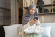 © Art_Photo - Asian muslim woman use smartphone at home, female in hijab checking messages, modern communication, smiling and holding mobile device technology use, staying connected, lifestyle concept, social media