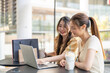 © Art_Photo - Two diverse women smiling and talking while use laptop for online shopping at cafe, searching for deals and discounts with shopping bags on table, concept of e-commerce, retail, digital lifestyle