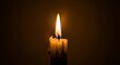 © Ilham - Single candle flame burning brightly against dark brown background