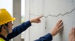 © Mei Studio - Construction worker examining and pointing at a crack in a concrete wall