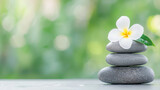 Serene spa moment with stacked stones and white flower, symbolizing tranquility and relaxation in natural setting