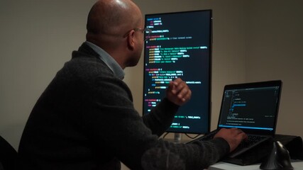 Side view male programmer wearing glasses works late at night with green code reflecting on his lenses, focusing on software development, coding, and cybersecurity analysis.