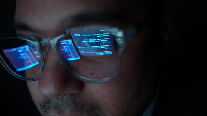 Close-up Reflection green code in lenses of glasses and eye of Male programmer works late at night, focusing on software development, coding, and cybersecurity analysis in dark room.