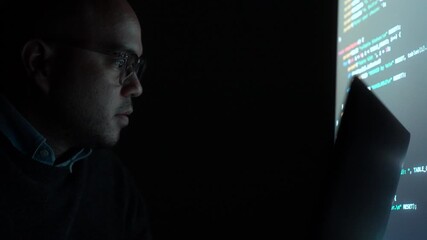 Close-up Reflection green code in lenses of glasses and eye of Male programmer works late at night, focusing on software development, coding, and cybersecurity analysis in dark room.