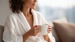 © Yulia - Relaxed woman in robe holding tea with visible arm metabolic patch, serene home wellness scene, Metabolic Patches visual