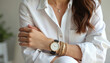 © Viktor - Young woman wears white casual shirt displaying elegant wrist with gold watch, bracelets. Details include necklace, subtle background. Focus on feminine style, modern accessories, timeless glamour.