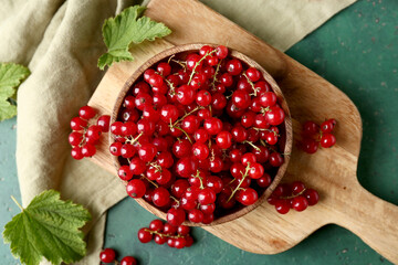 Wall Mural - wooden cutting board and bowl with fresh red currants on green grunge background, closeup